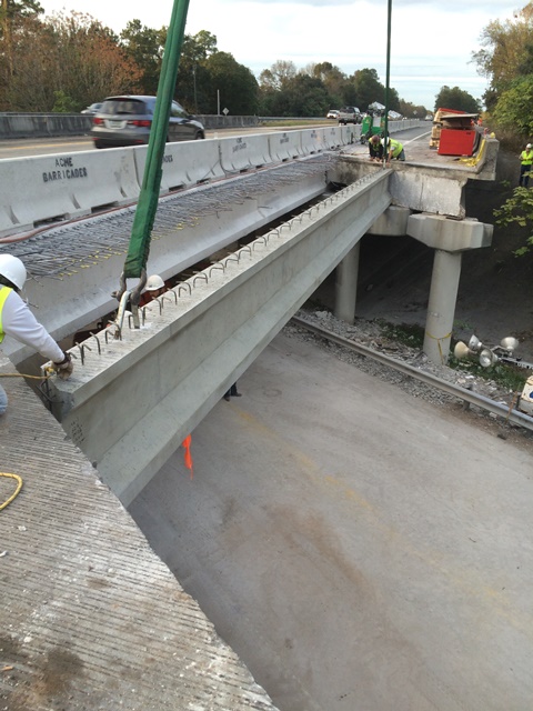 Workers install large concrete beam on bridge construction site