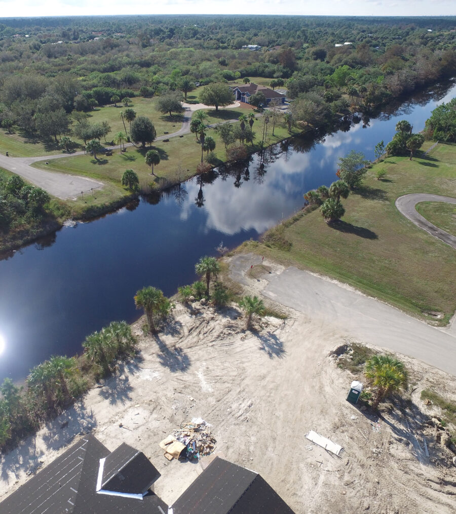 Aerial view of a house beside a winding river surrounded by trees and open grassland