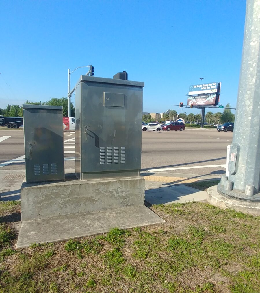 Traffic control boxes at a busy street intersection with blue sky