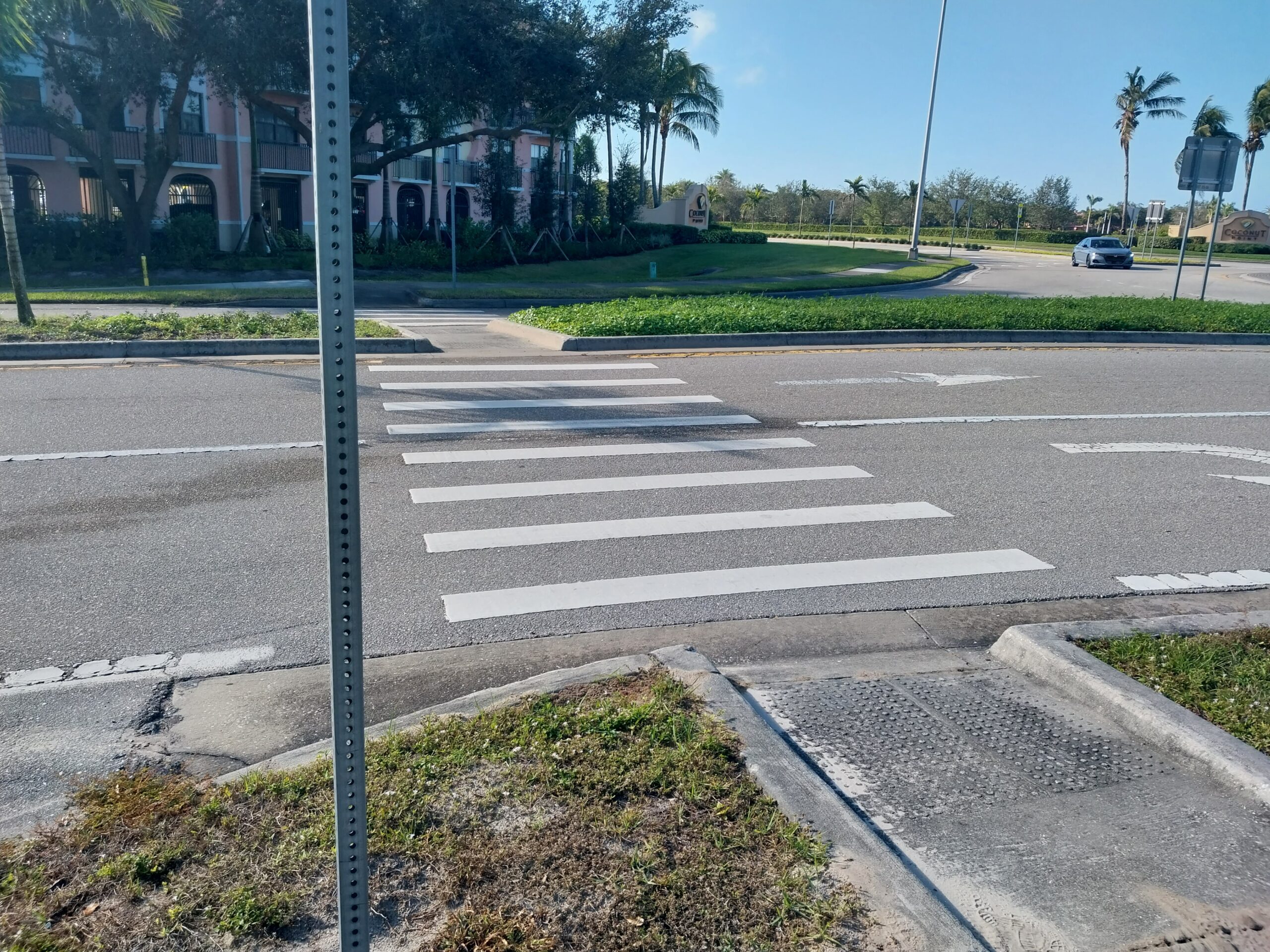 Crosswalk on a sunny street with a car approaching in the background