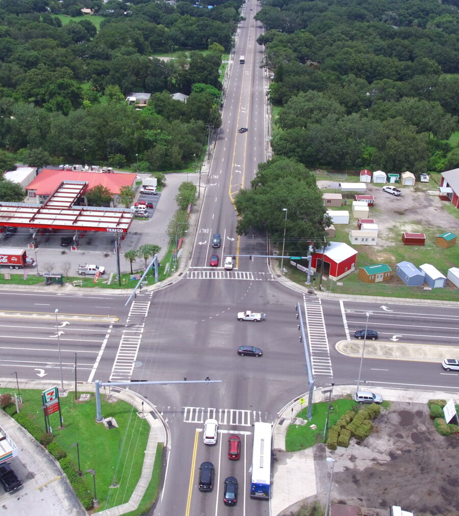 Aerial view of a busy intersection surrounded by trees, businesses, and parked cars