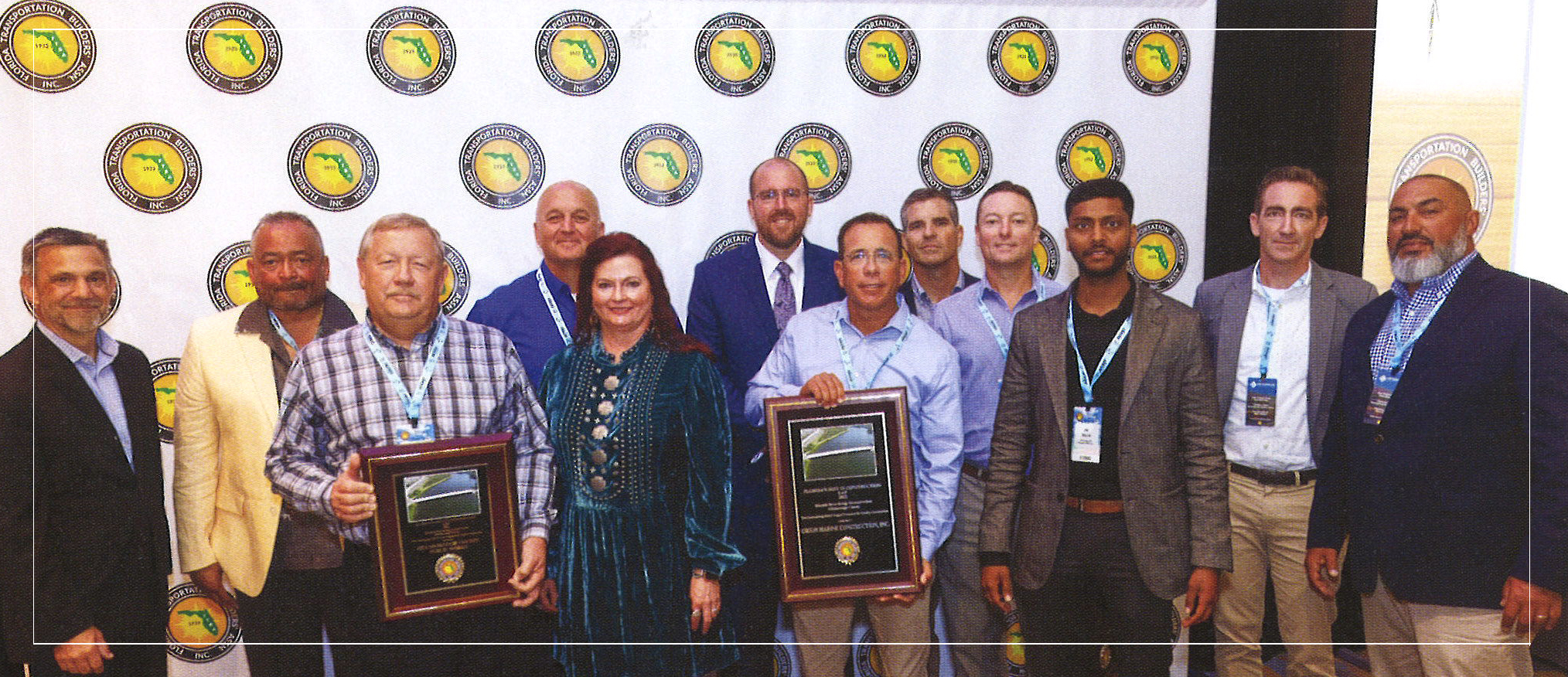 Group of diverse award recipients holding plaques, smiling at a Florida Transportation Builders Inc. event