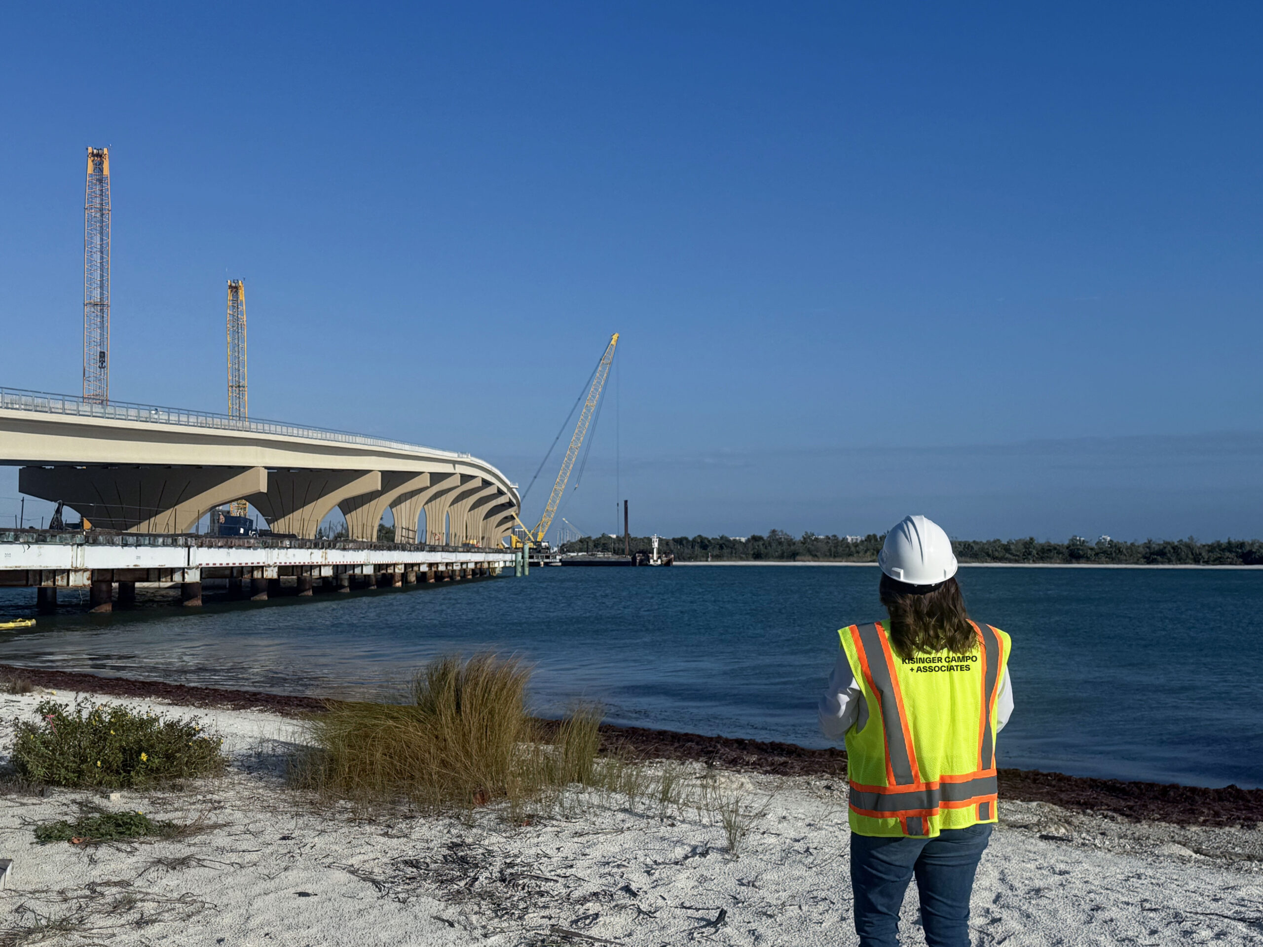 Person in safety gear observing bridge construction over water