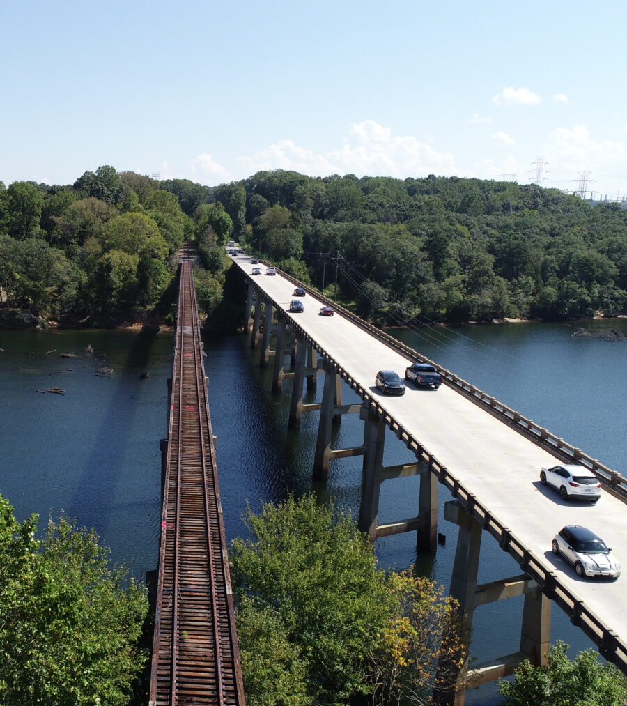 Cars driving on a bridge alongside a parallel railway track over a river