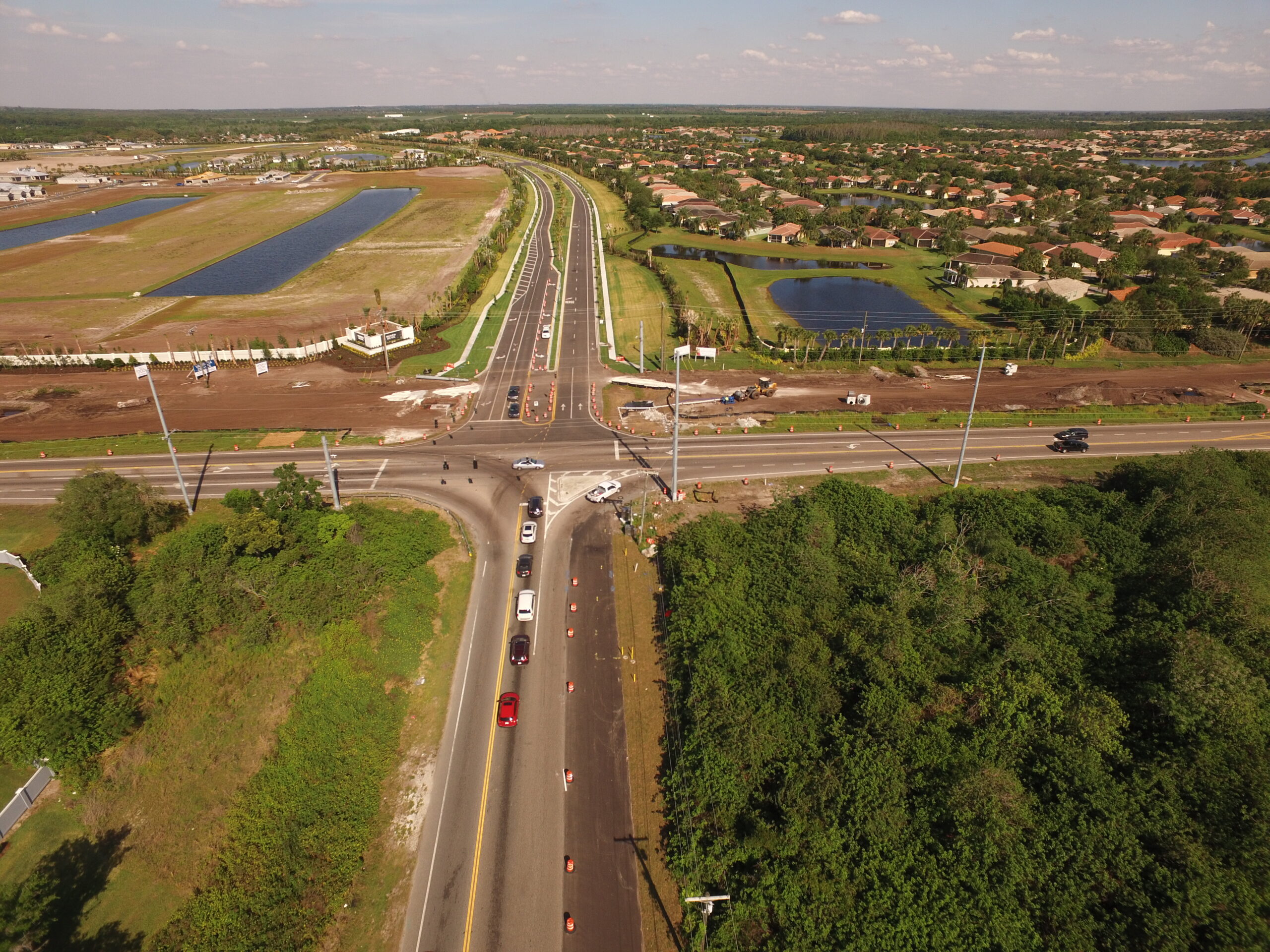 Aerial view of a crossroads under construction with vehicles and surrounding residential area