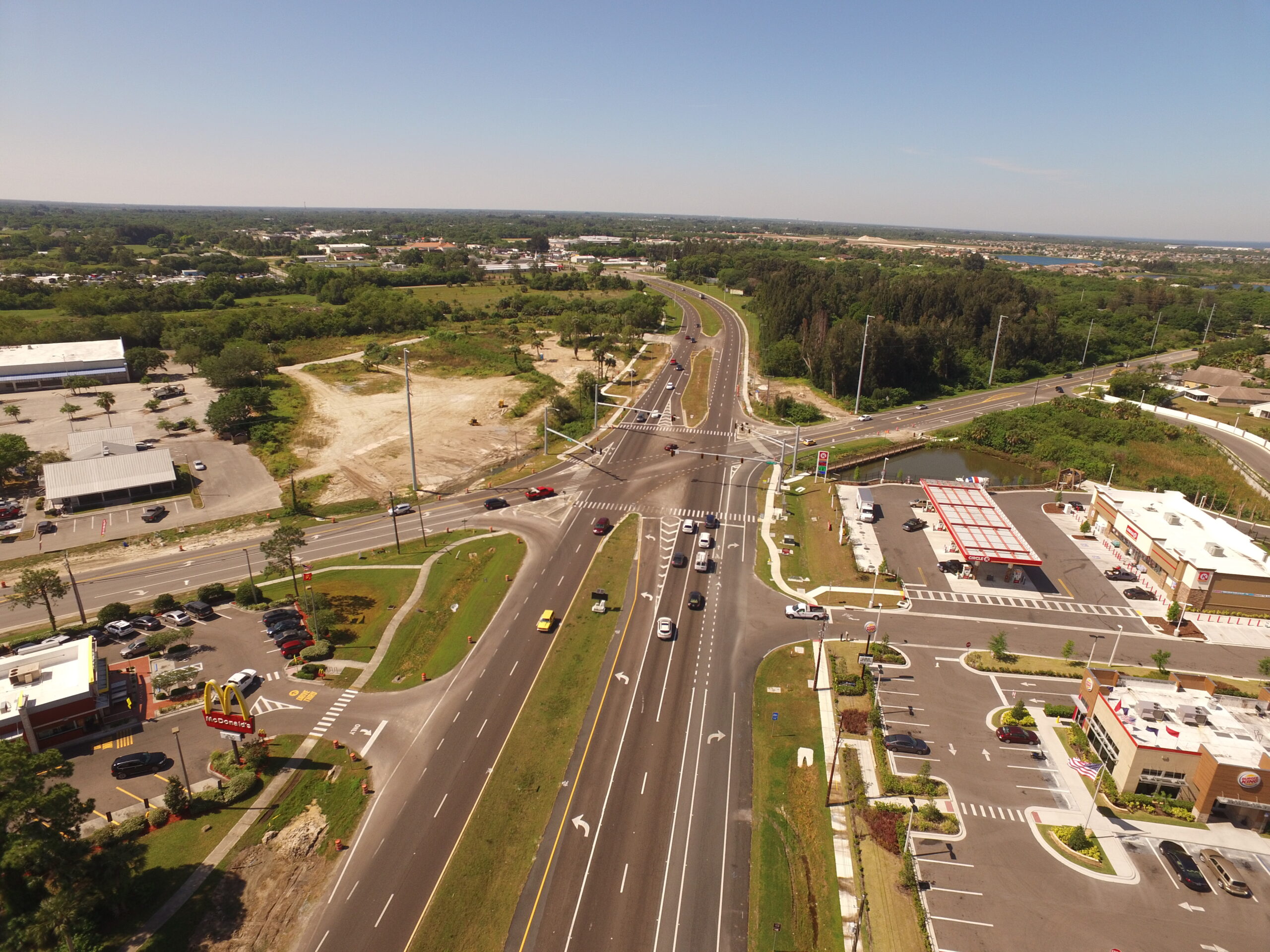 Aerial view of busy intersection with McDonald's, Taco Bell, and gas station surrounded by greenery