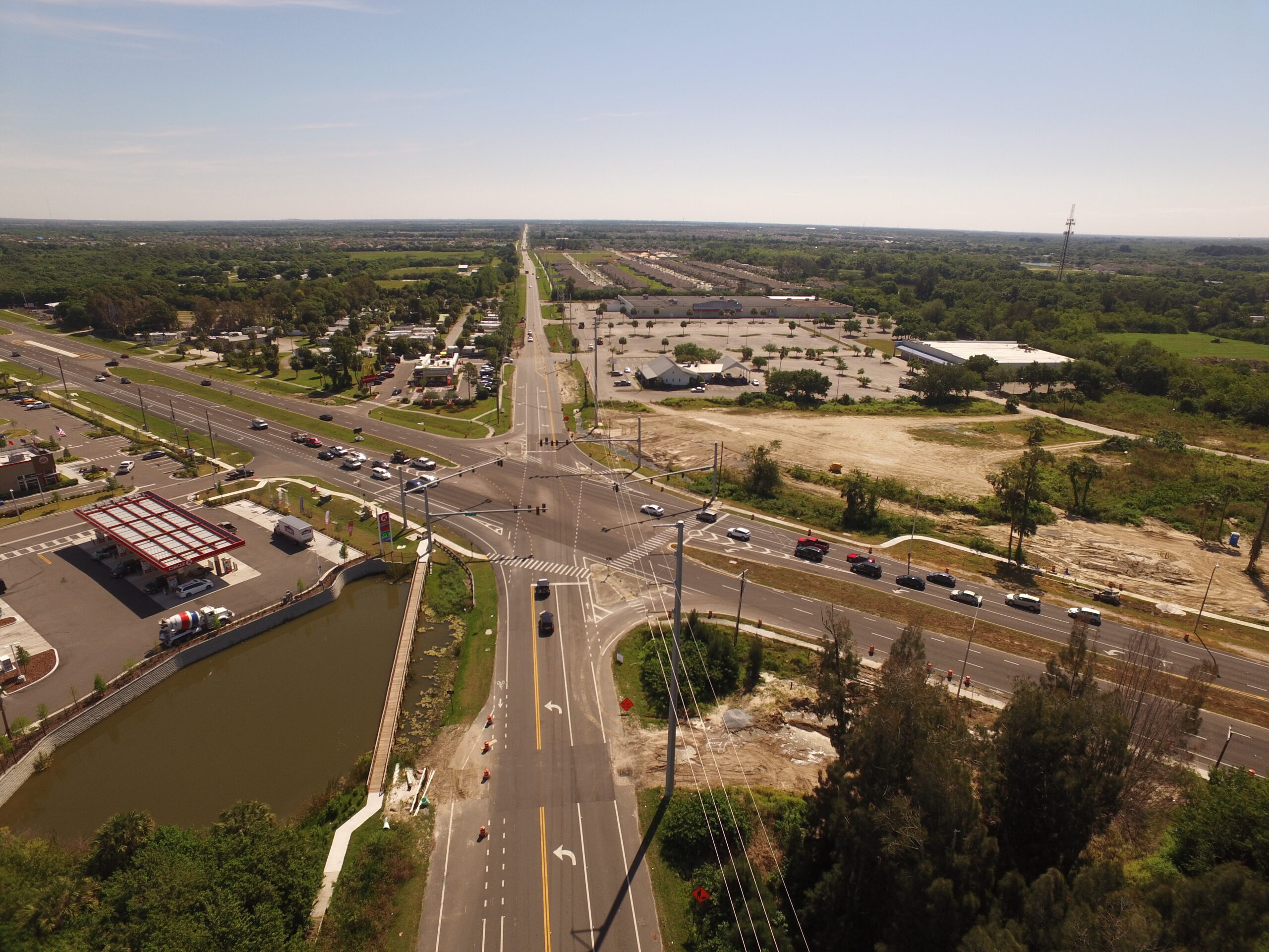 Aerial view of a busy intersection with surrounding greenery, buildings, and a gas station on the left