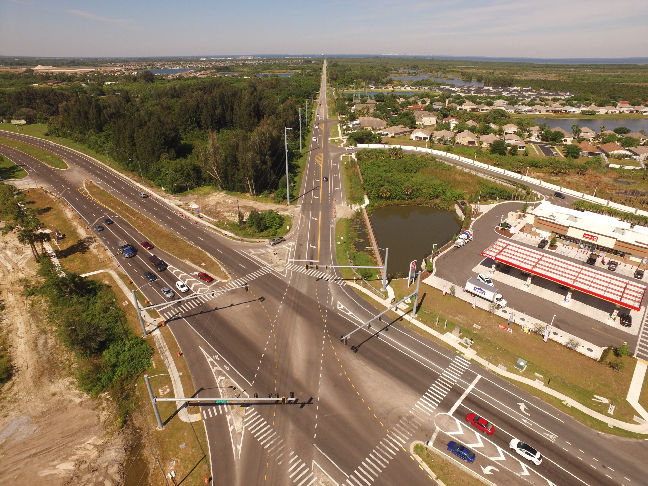 Aerial view of an intersection with traffic, gas station, and nearby residential area