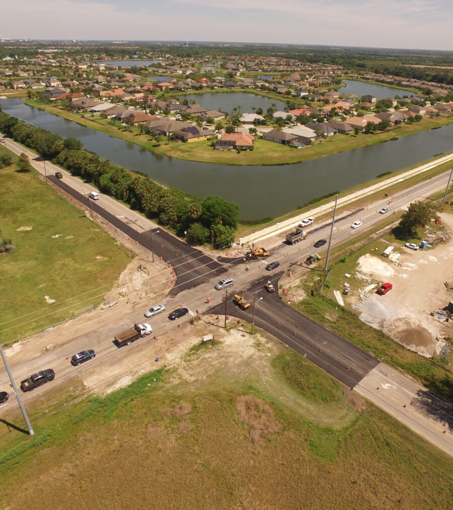 Aerial view of road construction and traffic near a residential area with adjacent waterways
