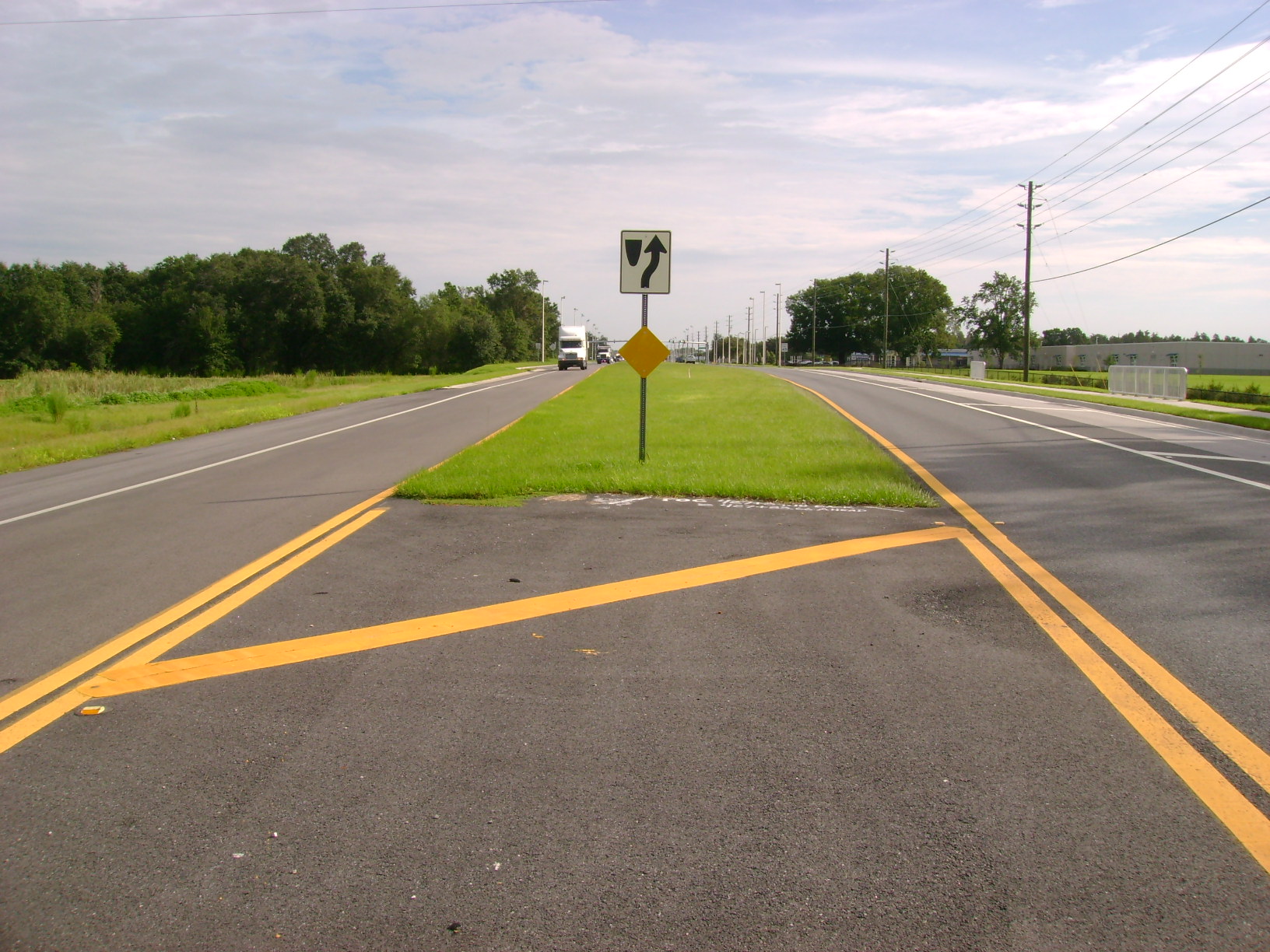Road with a grass median and left-turn arrow sign