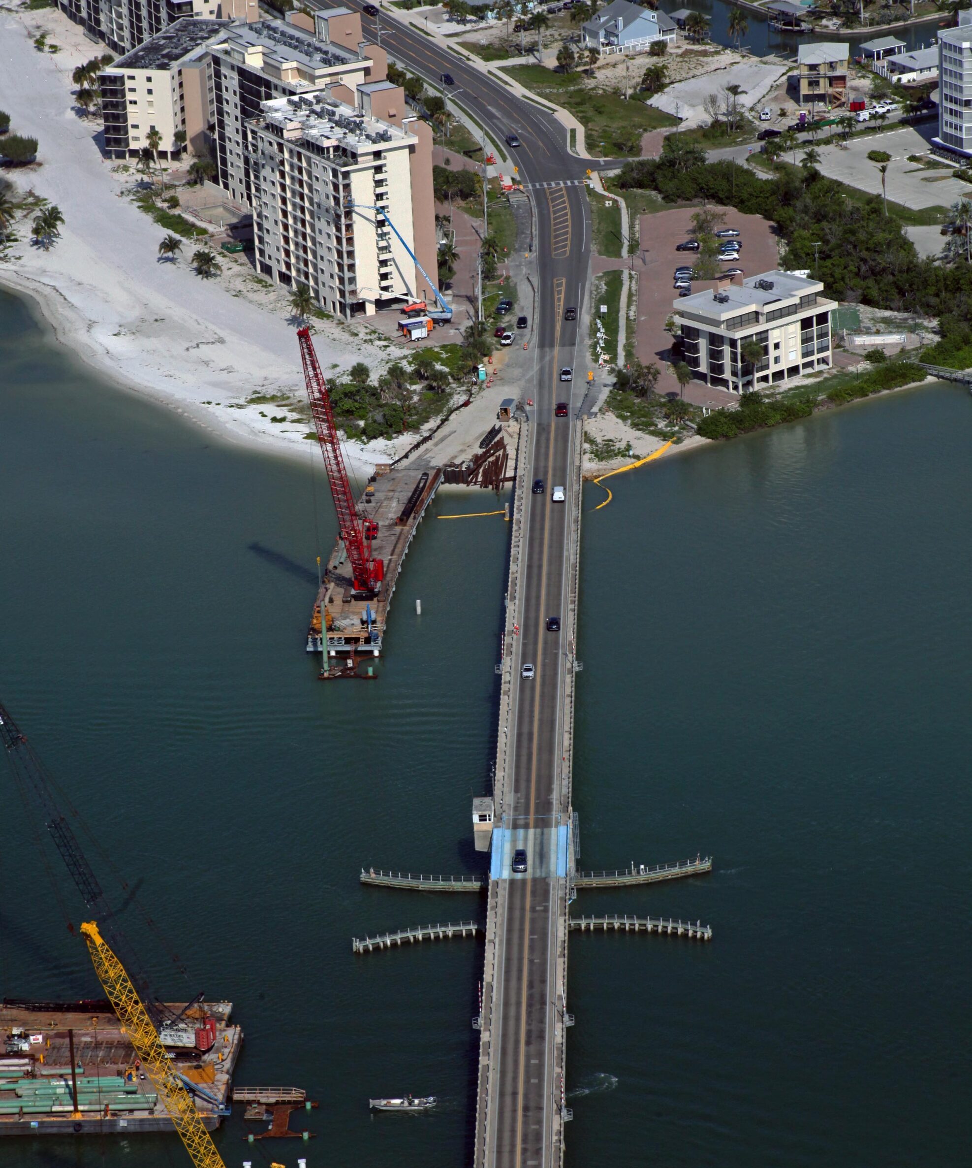 Aerial view of Estero Blvd bridge; construction crane on water; buildings and coastline visible