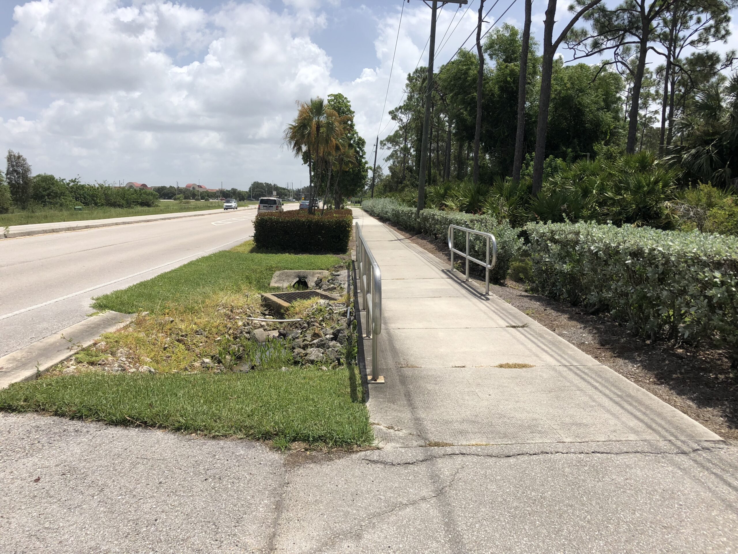 Sidewalk with railing beside a road on a cloudy day