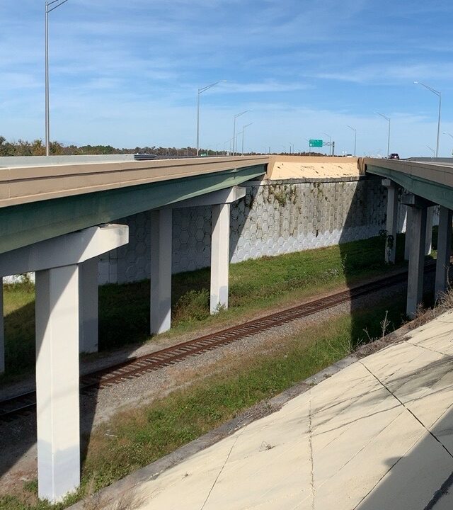 Highway overpass with a blue car, train tracks underneath. Text shows "Dec 9, 2019 at 1:32:29 PM FL-417 N Orlando FL 32832 United States"