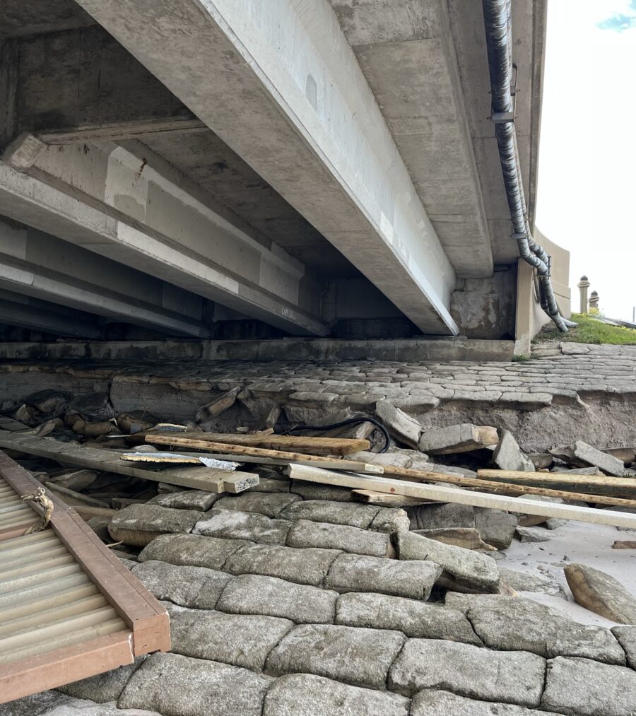 Bridge underpass with scattered debris and damaged bricks, clear sky visible