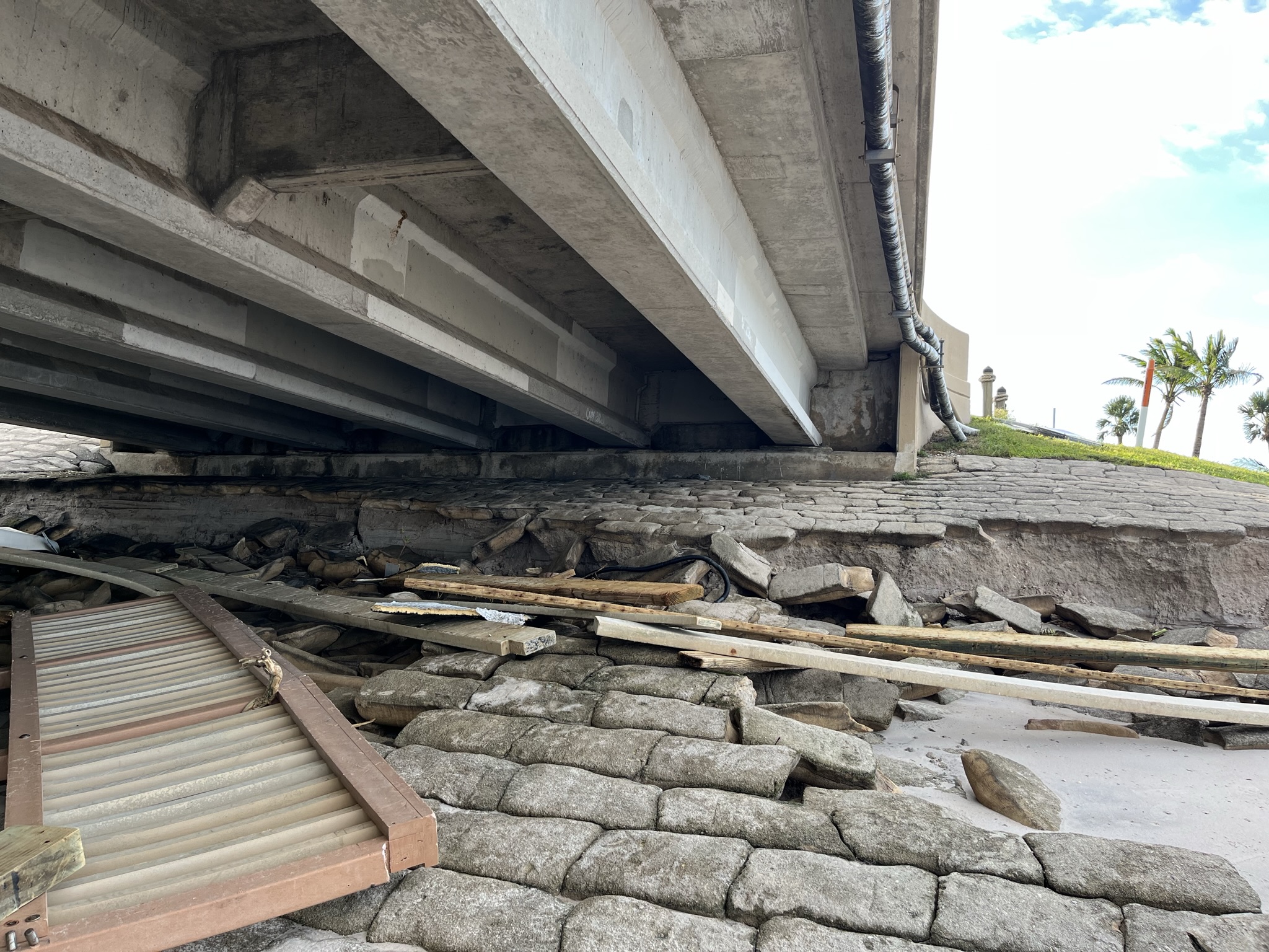 Bridge underpass with scattered debris and damaged bricks, clear sky visible