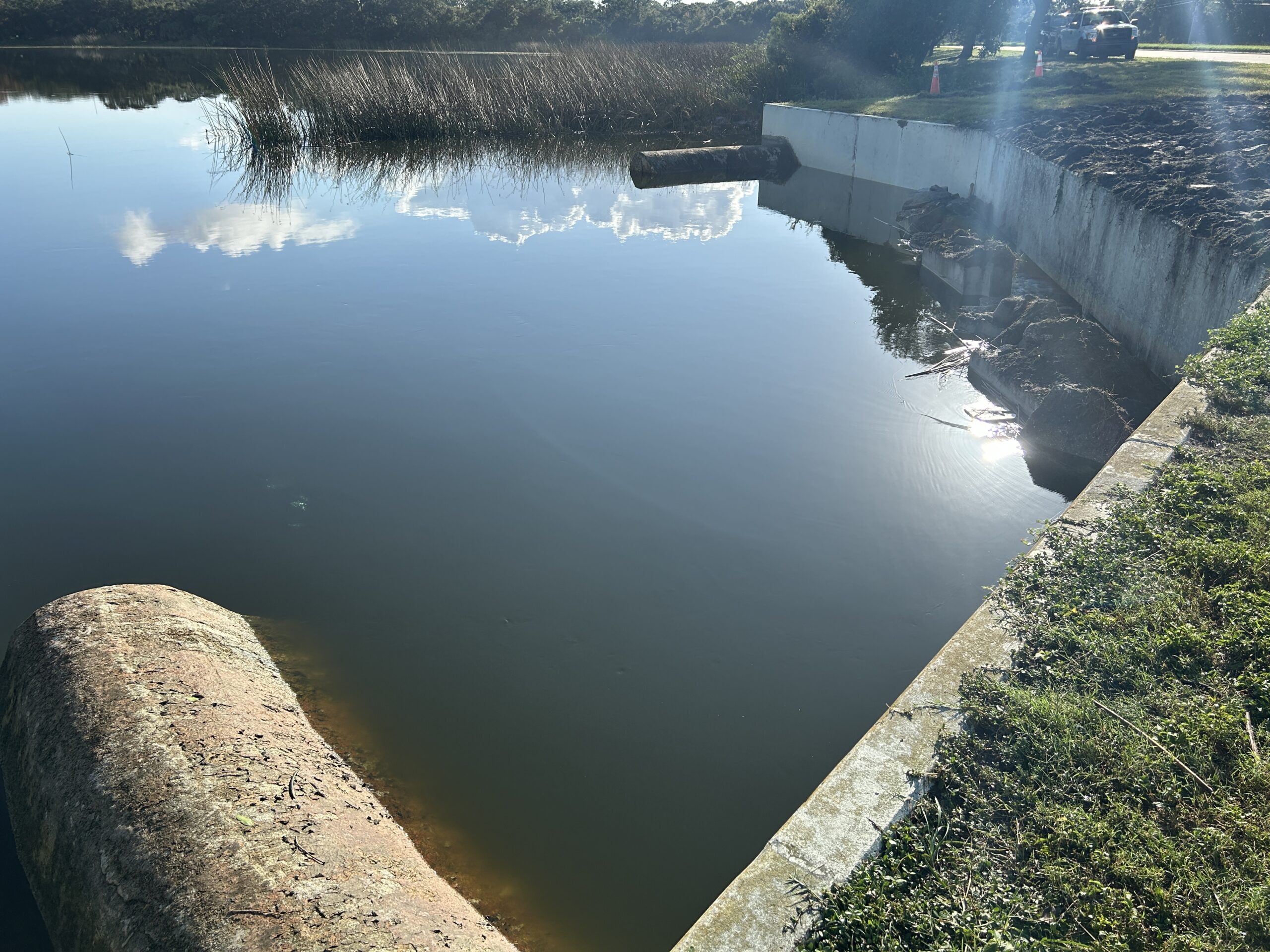 Calm lake with concrete banks and reflection of clouds
