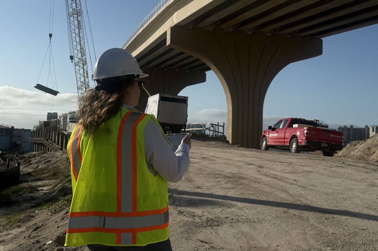 Construction worker in a hard hat and safety vest near a bridge