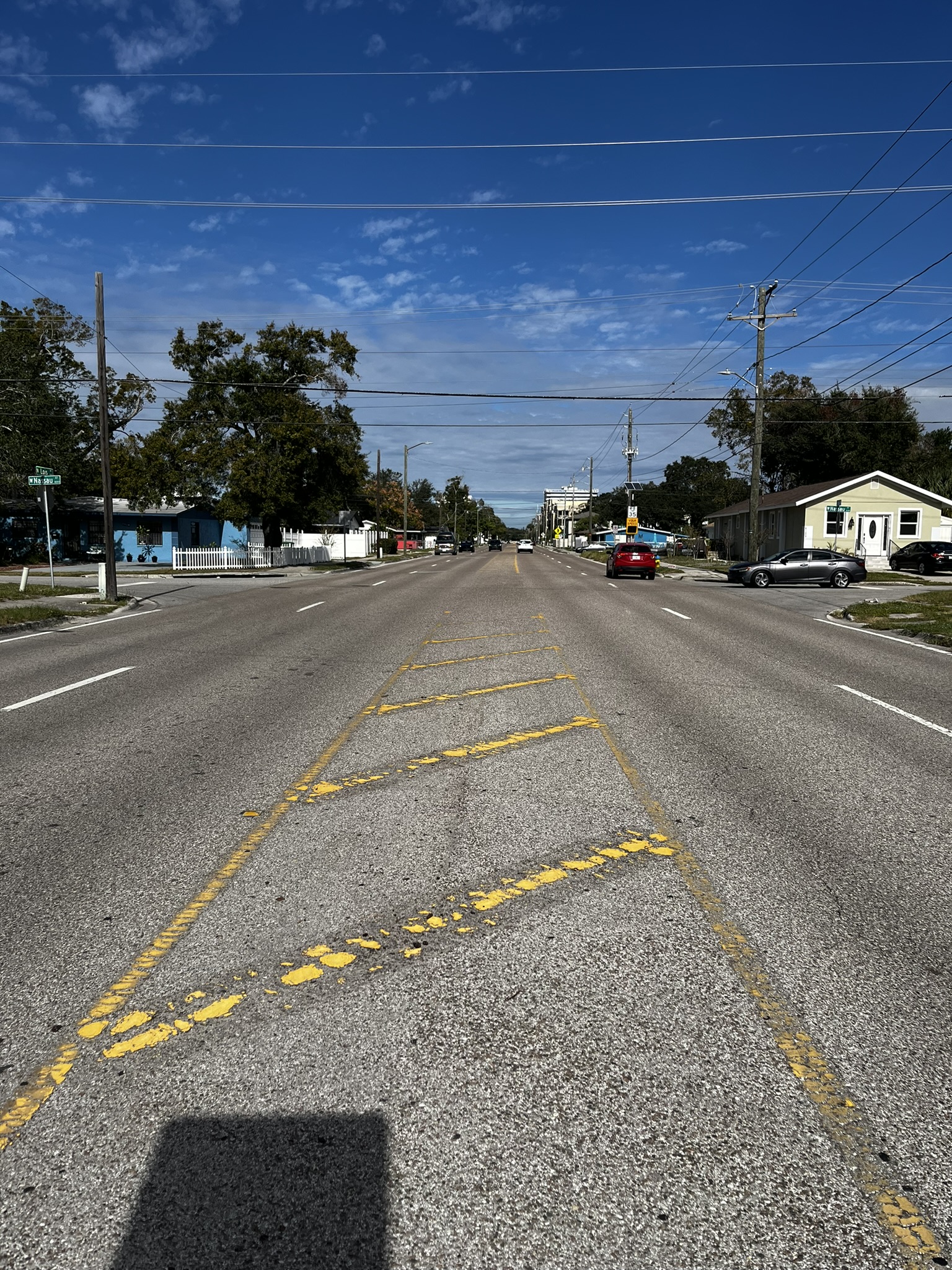 Sunny street view with houses and utilities, yellow road markings