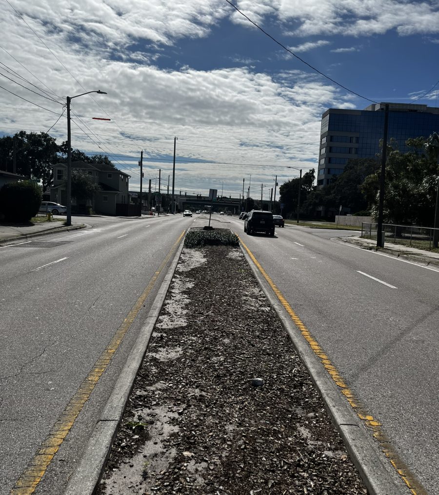 Empty road with cars, divided by central strip, under partly cloudy sky