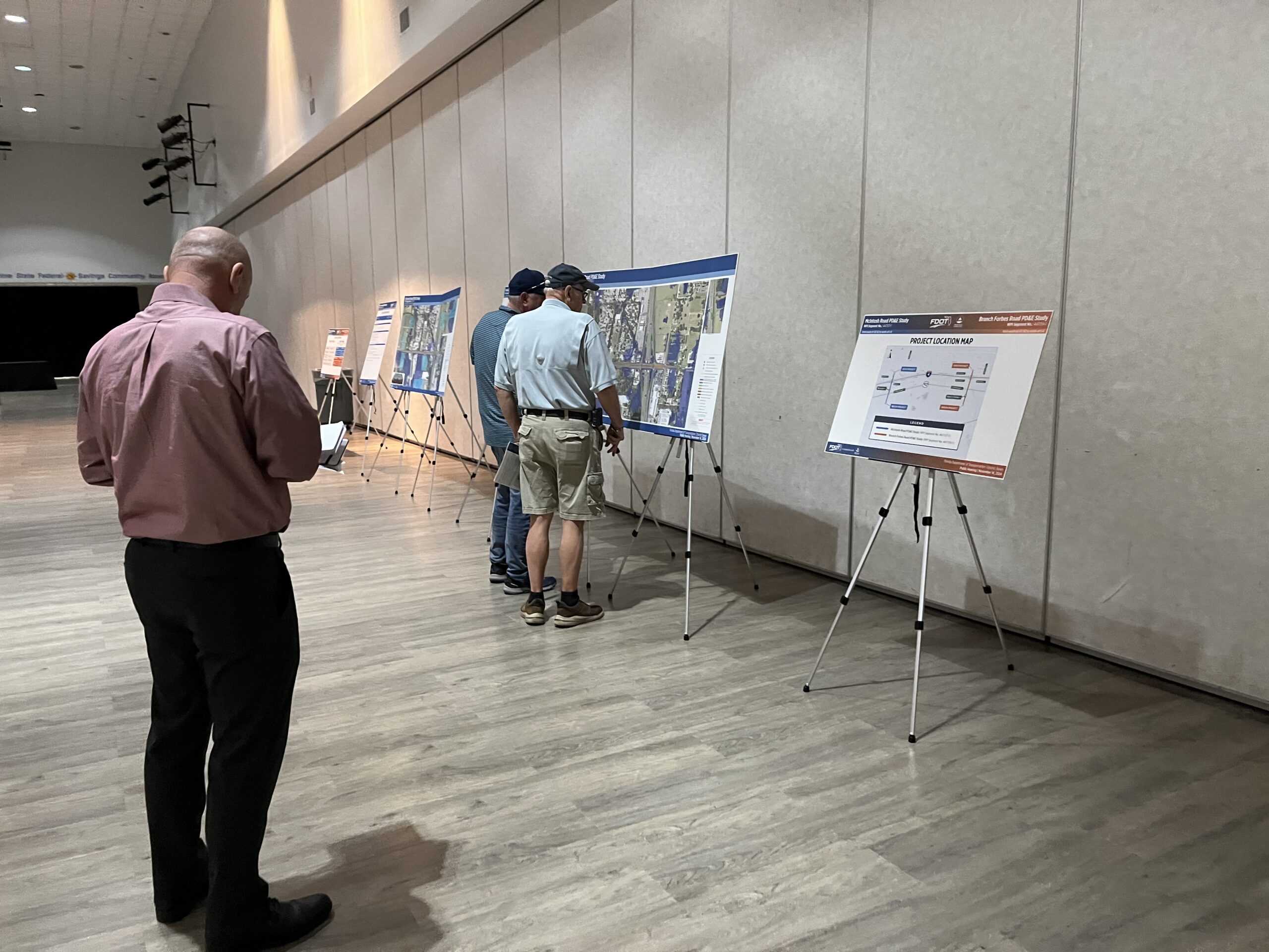 People viewing presentation maps and a penalty location map on easels in a conference room