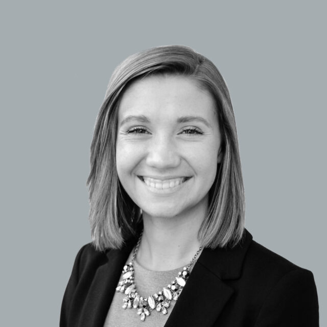 Jensen Andrea smiling in black and white portrait, wearing a necklace and dark blazer