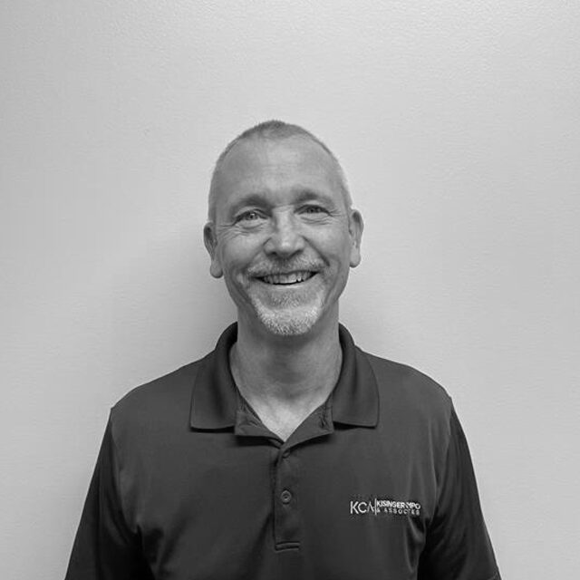 Jim Kelly smiling, wearing a polo shirt with "KCNR" embroidered
