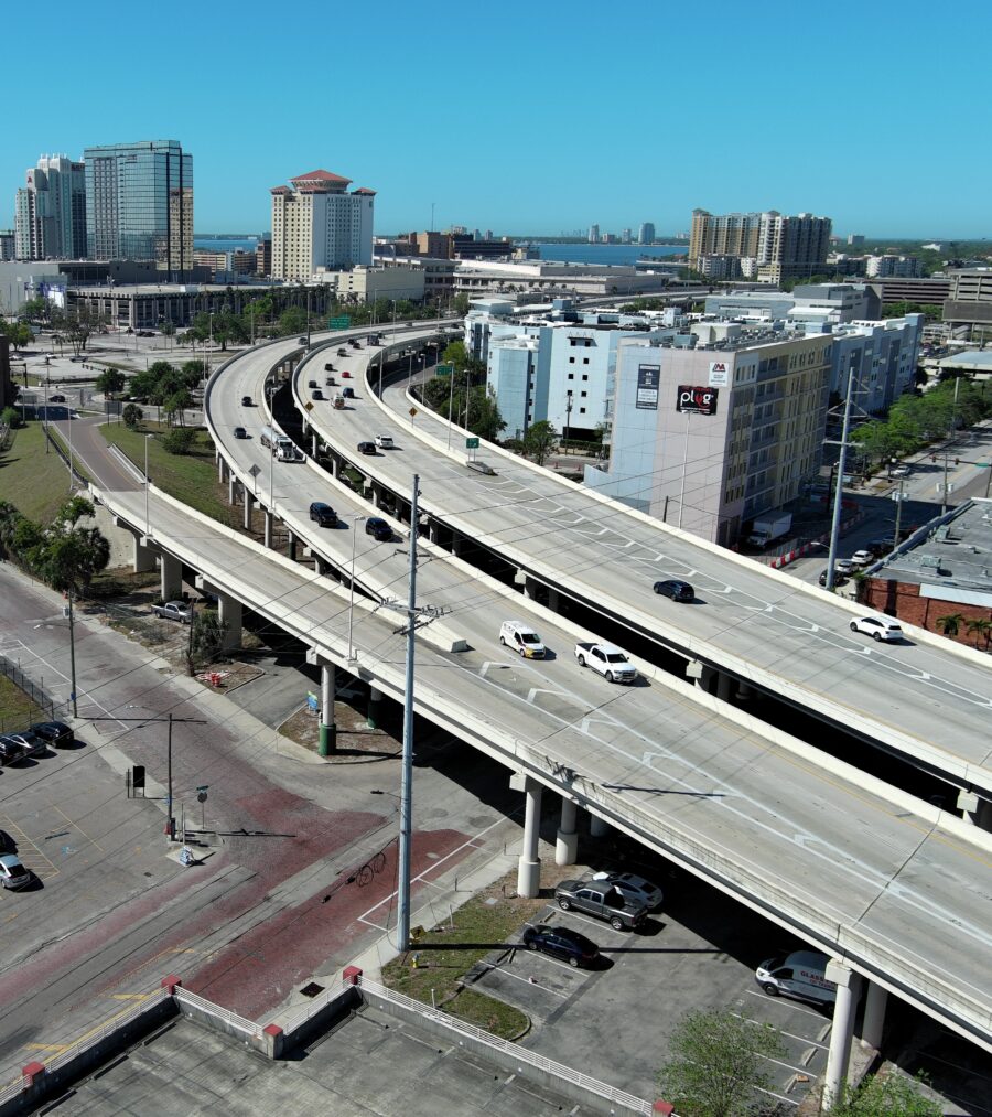 Highway overpass with flowing traffic, adjacent city landscape, and parking lots