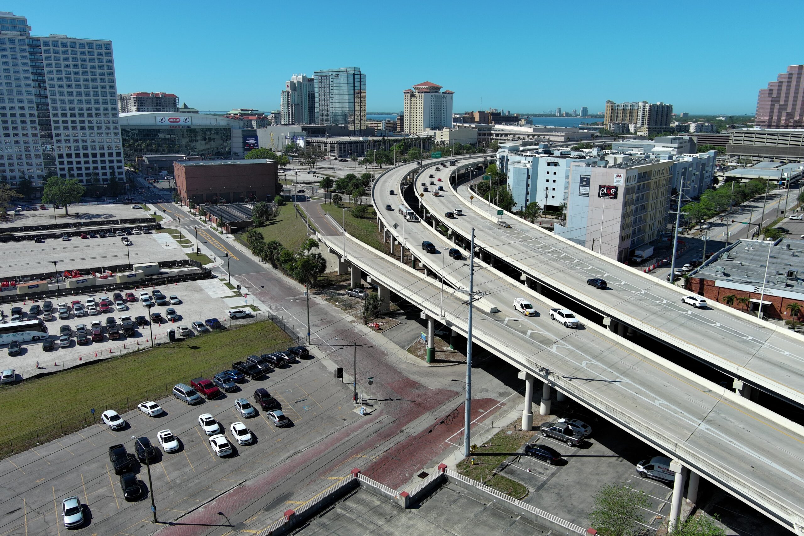 Highway overpass with flowing traffic, adjacent city landscape, and parking lots