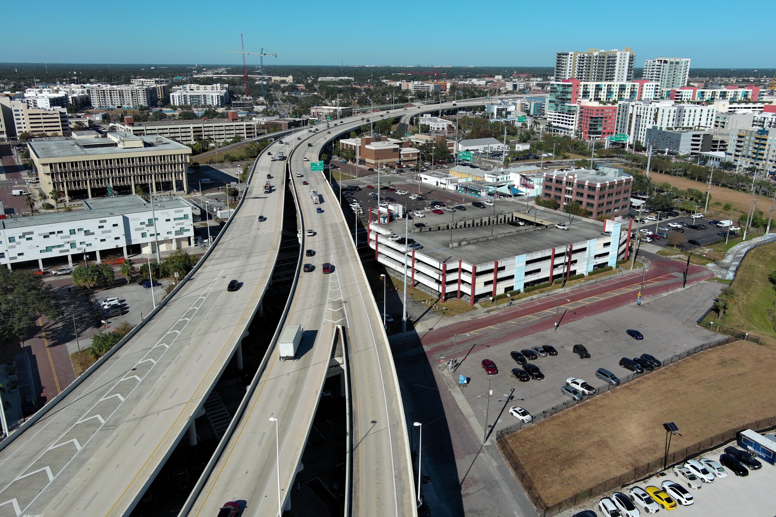 Highway overpass with light traffic amid urban landscape, surrounded by buildings and parked cars