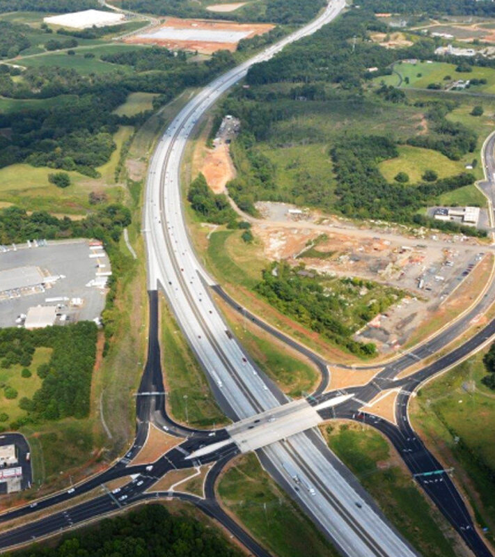 Aerial view of a highway interchange on Poplar Tent Road over I-85, surrounded by greenery and industrial areas