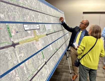 Man in suit explaining a large road map to attendees in a meeting room