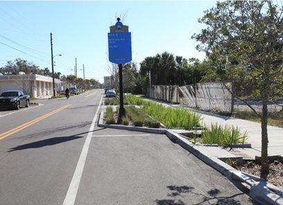 Roadway with a bicycle lane, street sign, and adjacent greenery