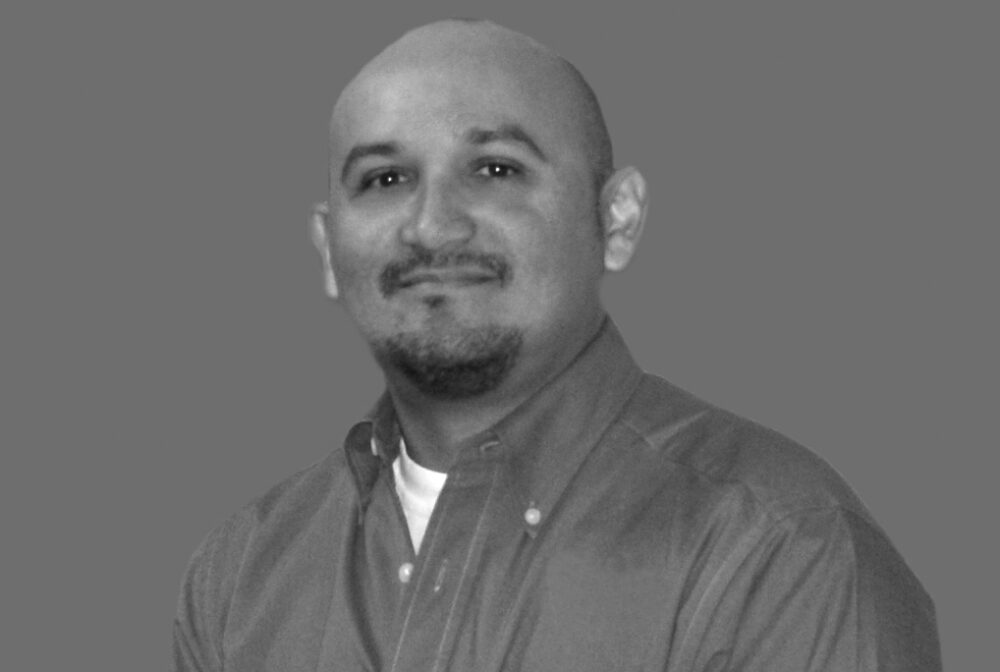 Rodriguez Antonio smiling in a black and white portrait wearing a buttoned shirt
