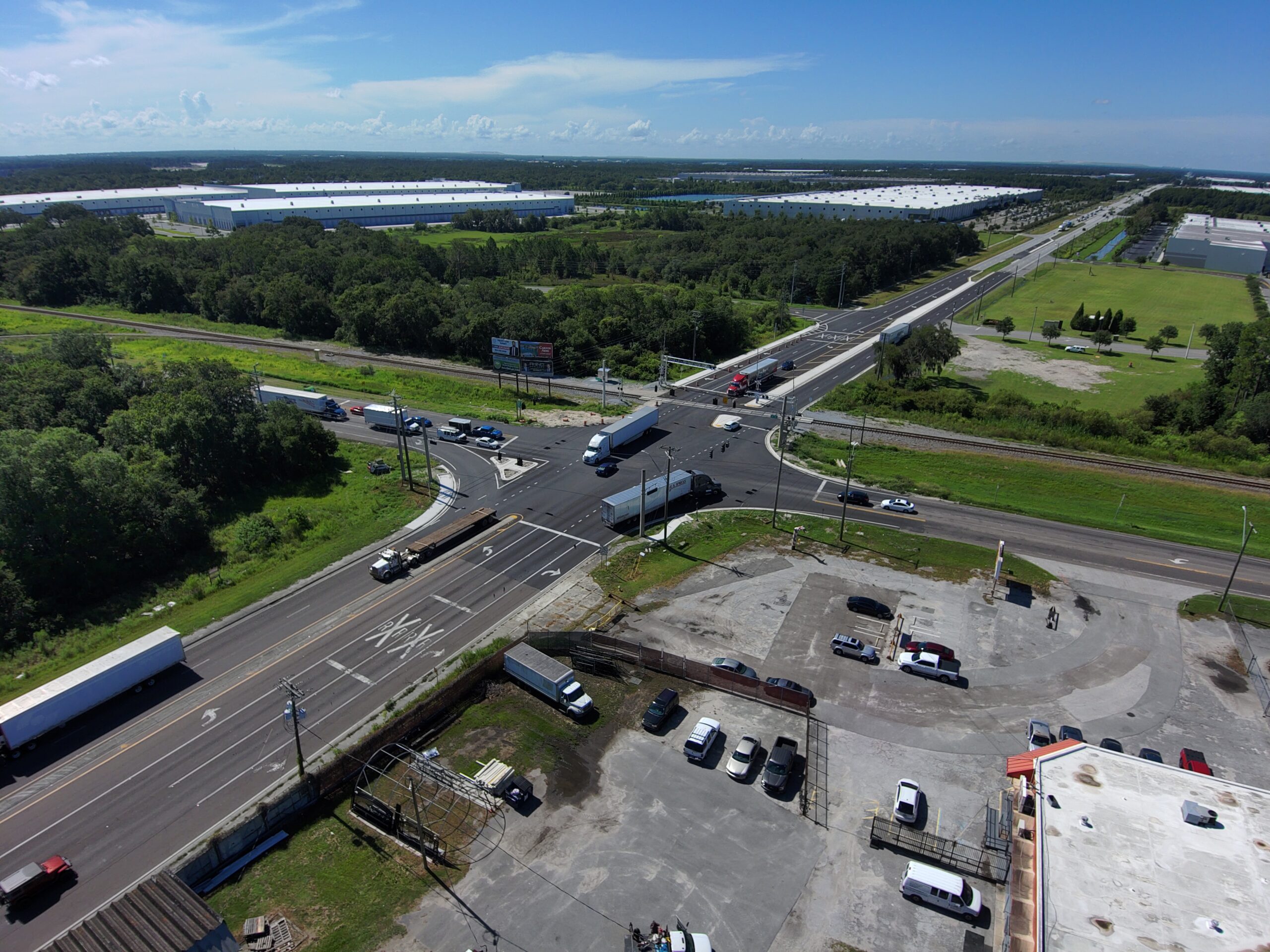 Aerial view of industrial complex with parking lot, trucks, and crossroads