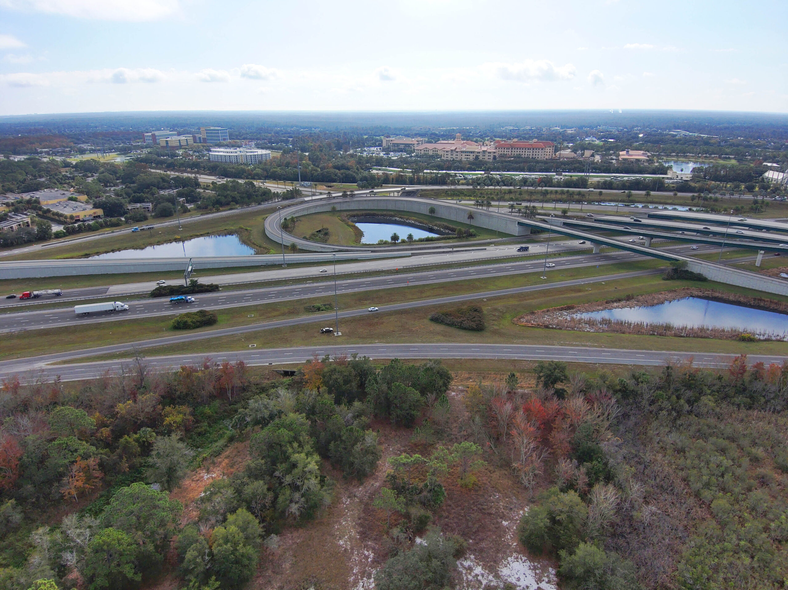 Aerial view of a highway intersection with multiple overpasses surrounded by trees and small ponds