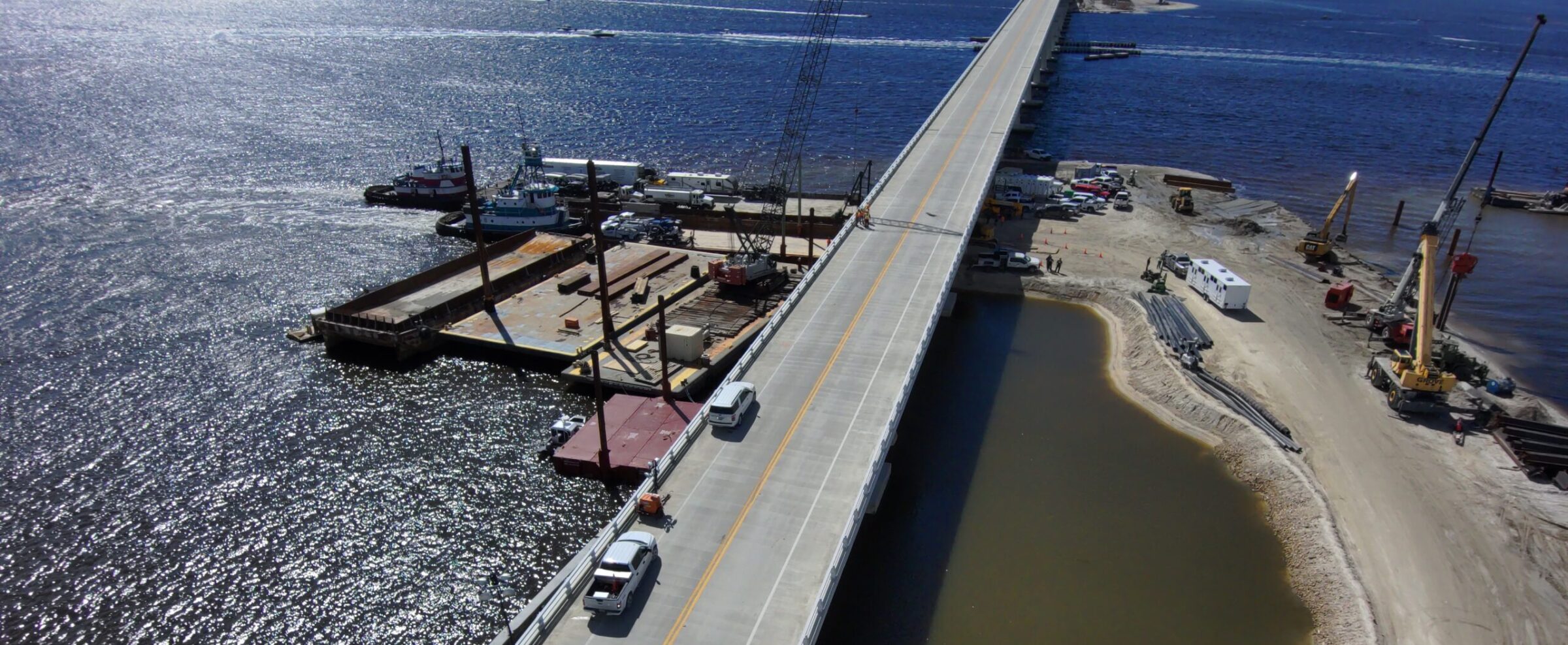 Aerial view of Sanibel Causeway under emergency repair after Hurricane Ian, with construction equipment and vehicles present