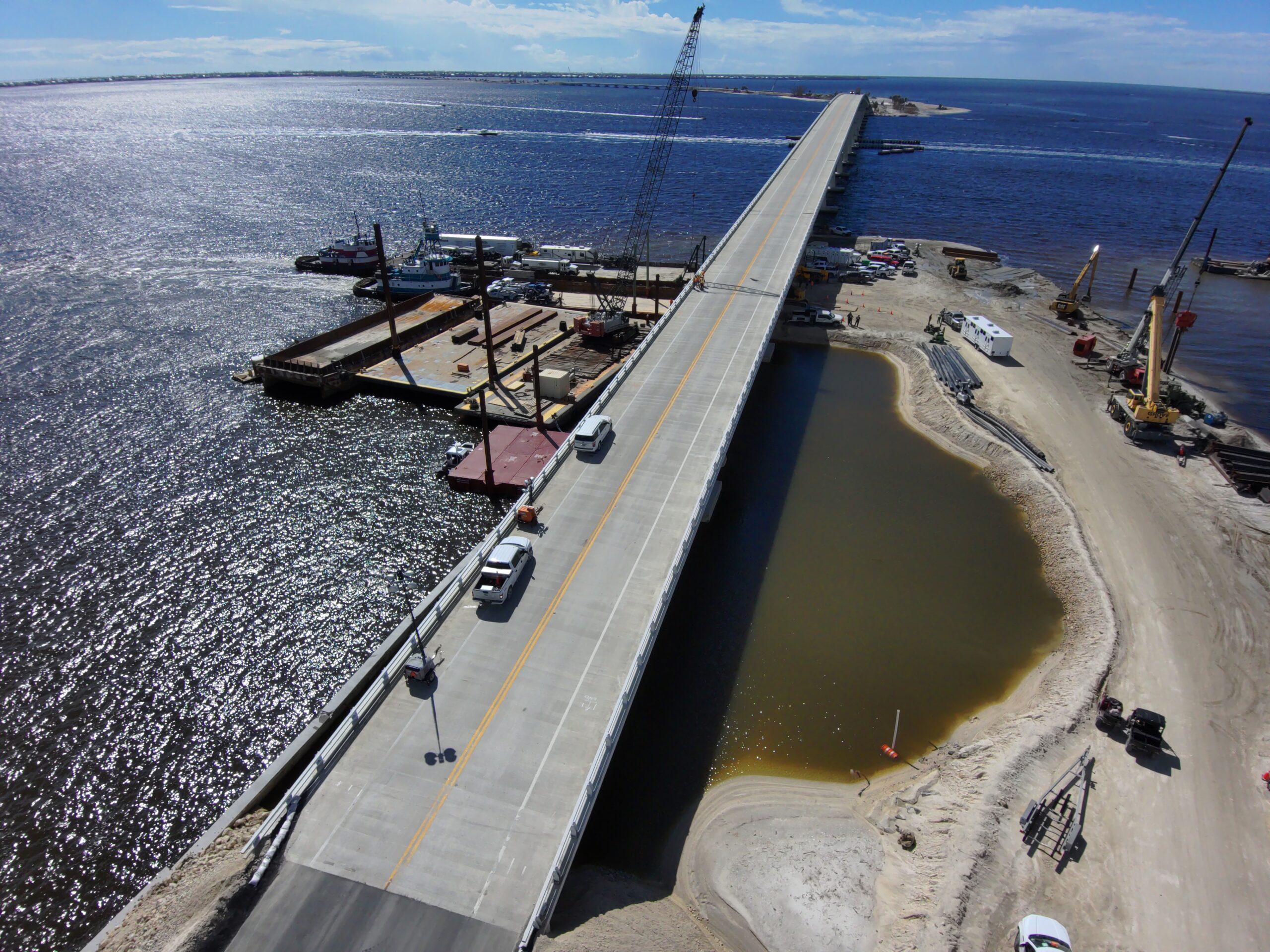 Sanibel Causeway under repair with construction vehicles, cranes, and water surrounding the area