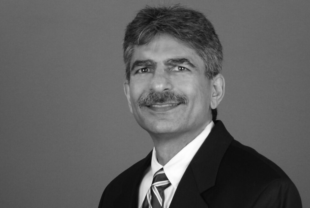 Tayebnejad Ali smiling, wearing a suit and striped tie