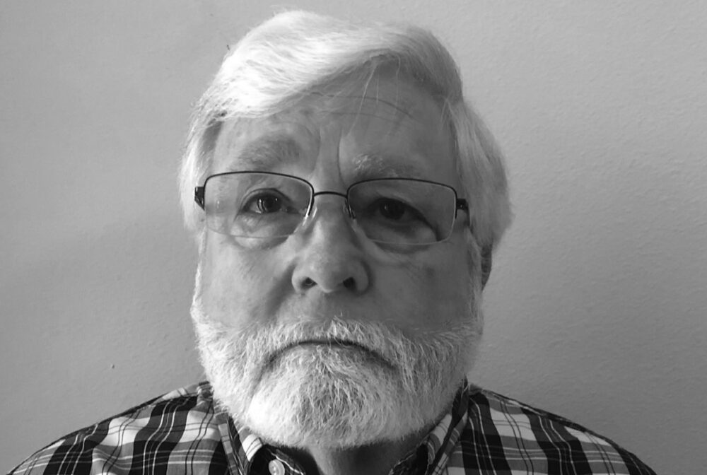 Timothy Heath, serious expression, gray hair and beard, glasses, plaid shirt