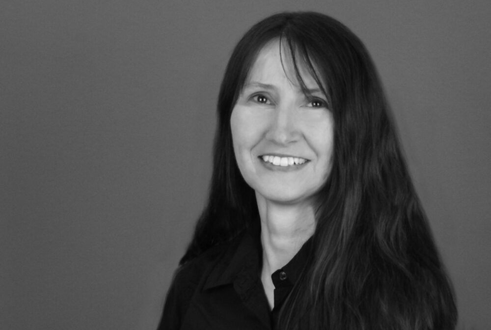 Donna Trew smiling in black and white portrait with long hair