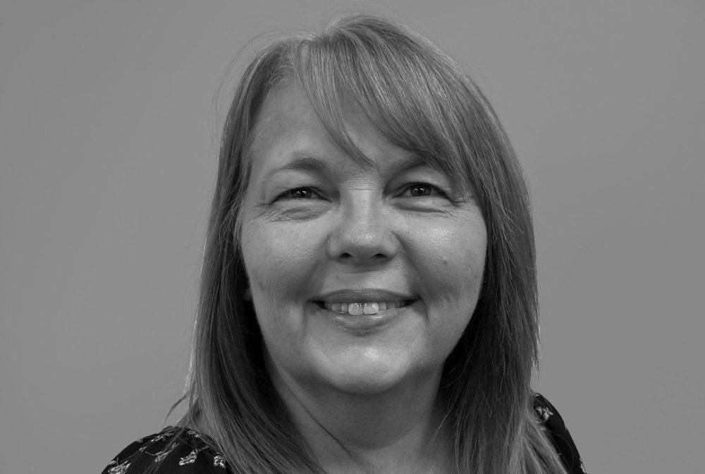 Smiling woman named Lori in floral blouse, black and white photo