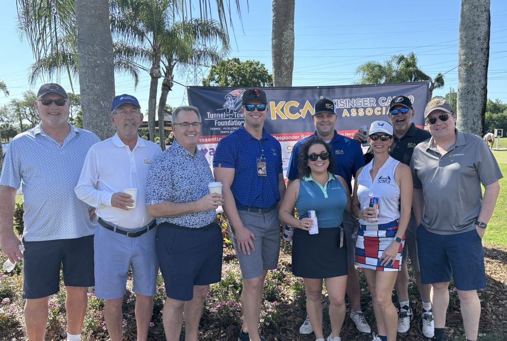 Group of smiling people at a golf event with Tunnels to Towers Foundation banner