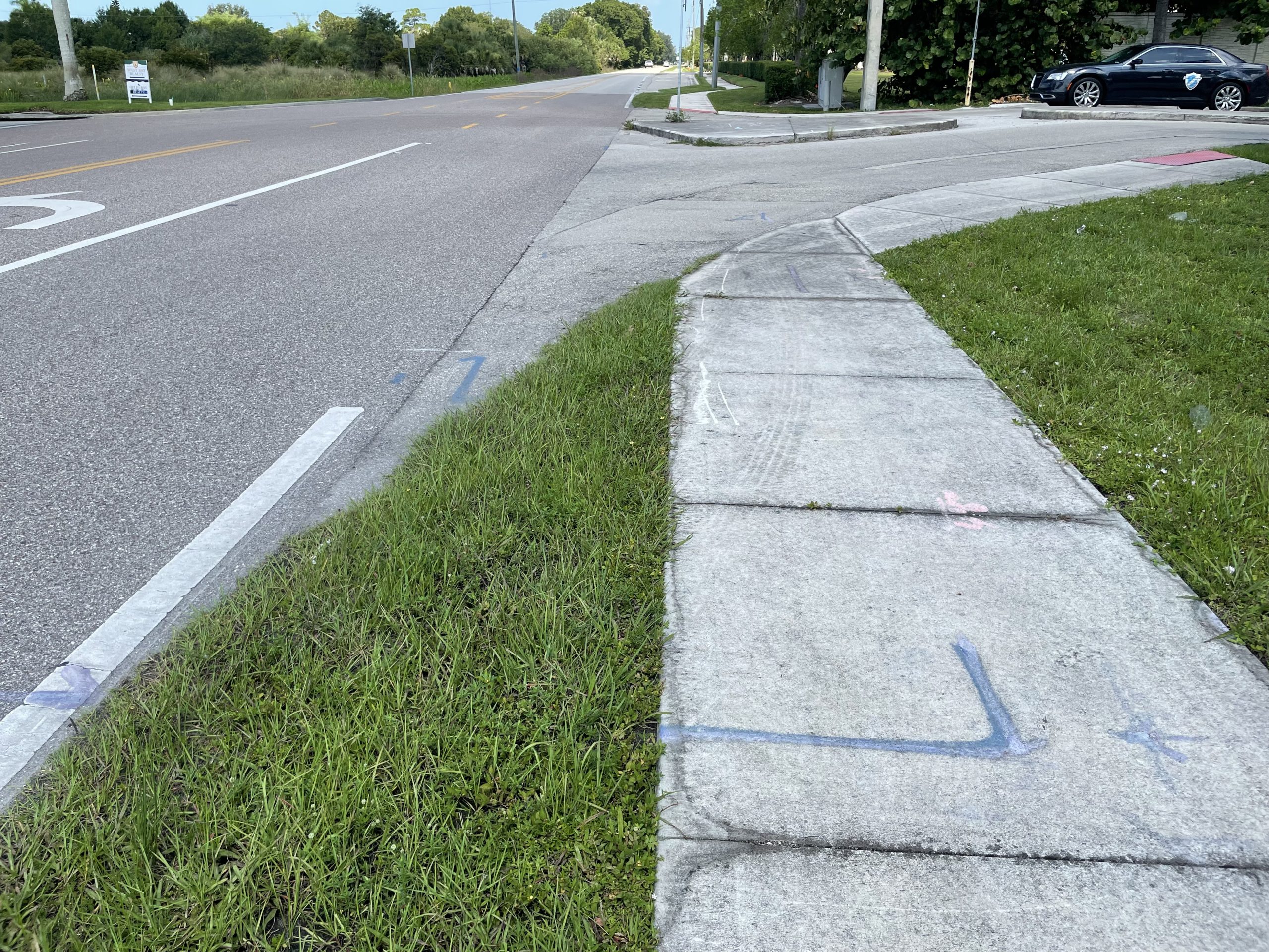Sidewalk ending abruptly at grassy area near a road